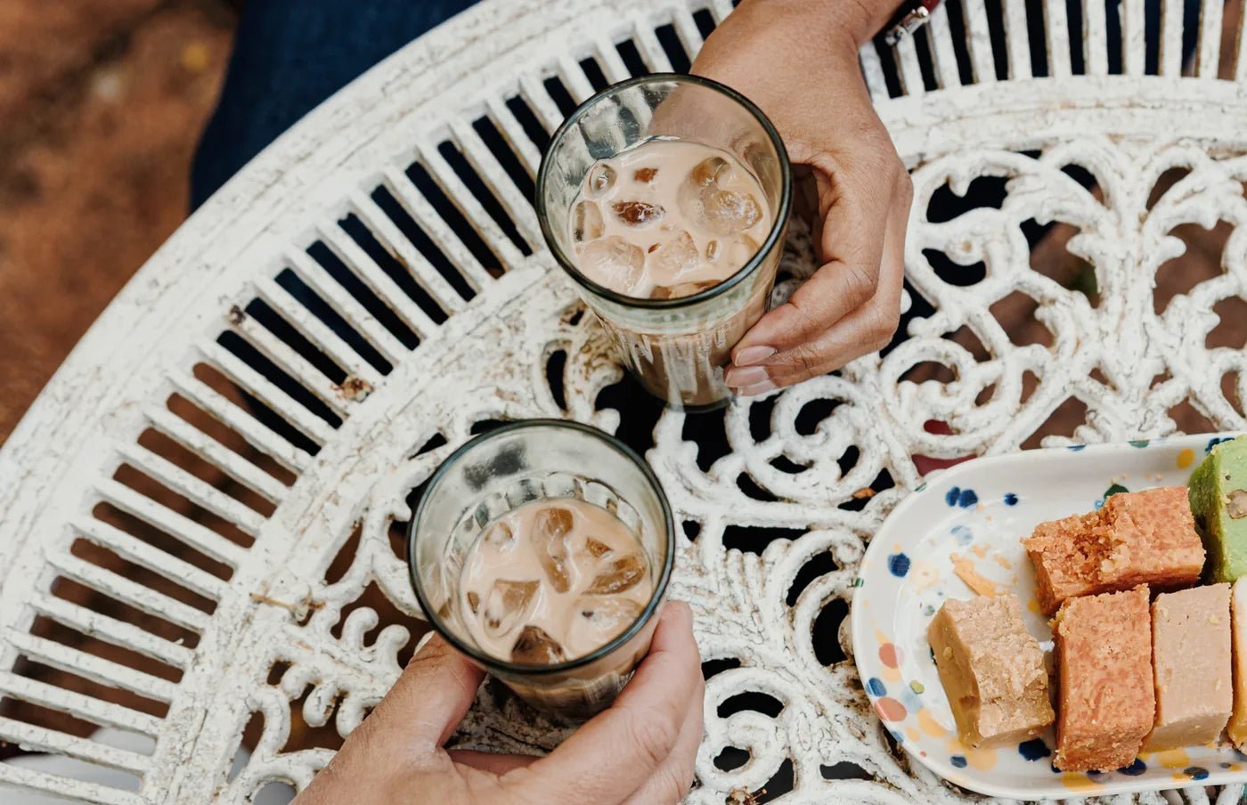 Two glasses of iced chai on a garden table